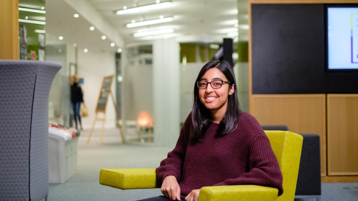 Smiling female student sat in a shared study area