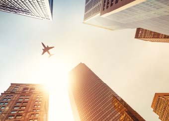 Skyscrapers with airplane flying across the sky