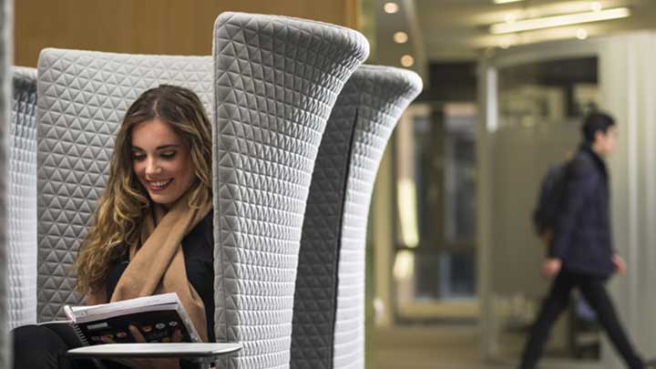 Female student sat down on chair reading in AMBS