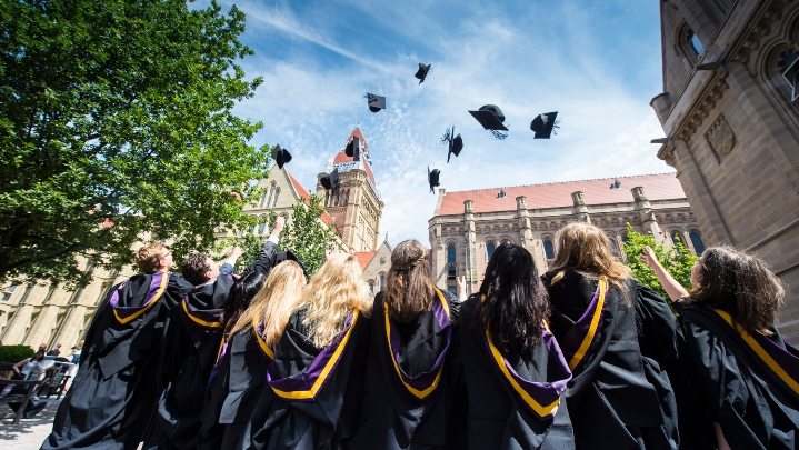 Students in graduation gowns throwing hats into the air.