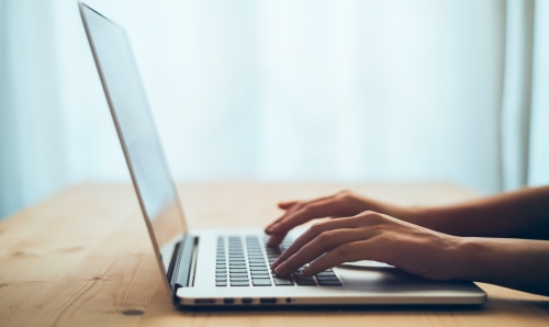 Hands typing on a laptop