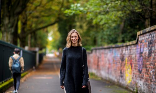 A student walking down a path in Fallowfield.