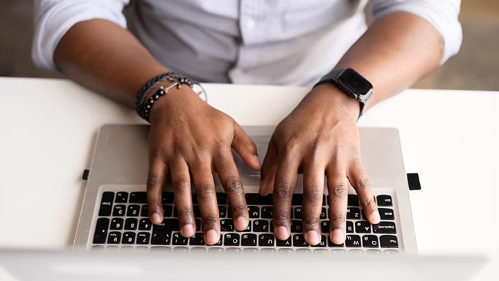 Hands typing on laptop