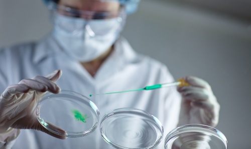 A scientist with pipette and green chemicals - iStock credit fotografixx