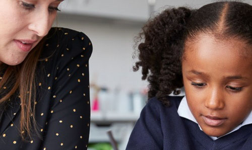 A teacher supporting a young student.