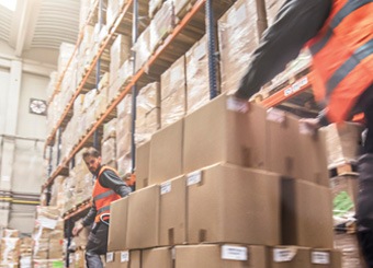 Two men pushing boxes in a warehouse