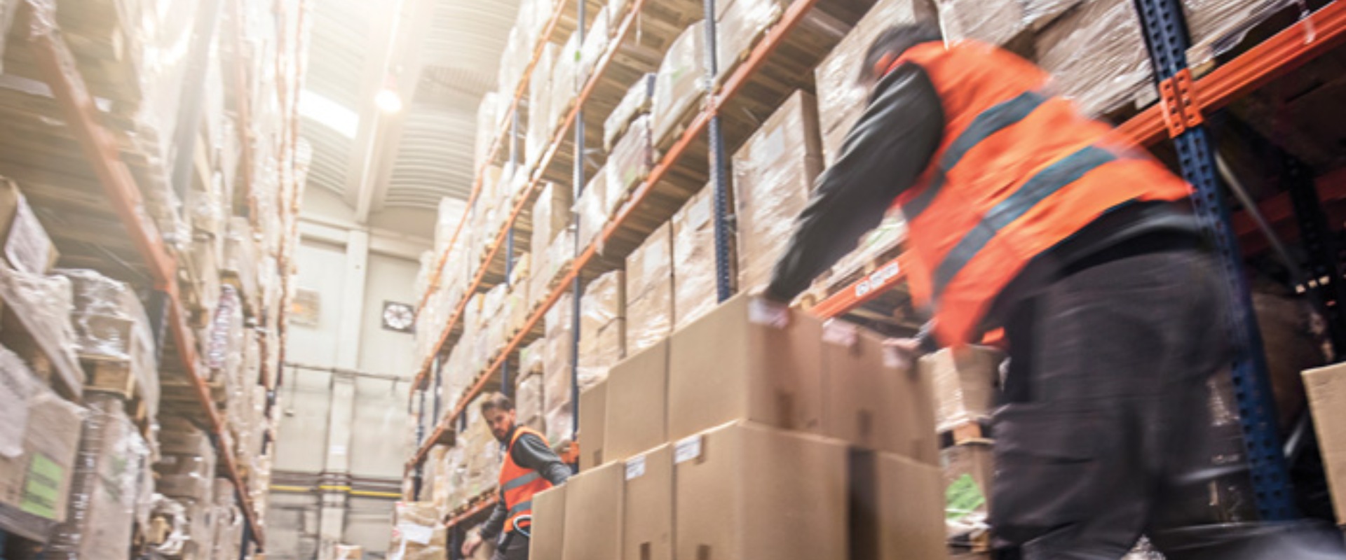 Two men pushing boxes in a warehouse