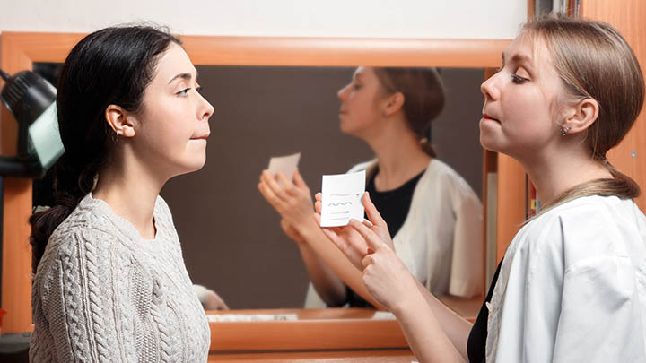 A therapist works with a patient on pronunciation.